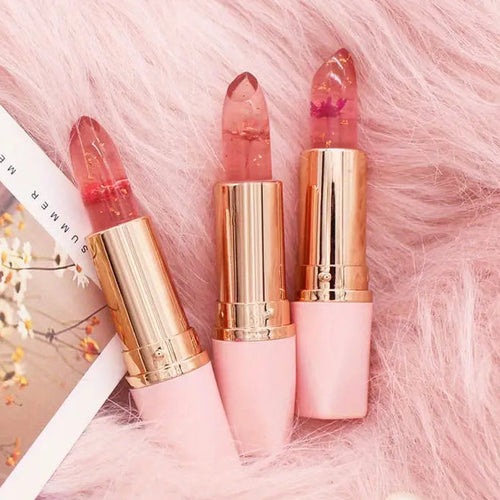 Three lipsticks with gold caps on a pink fluffy surface